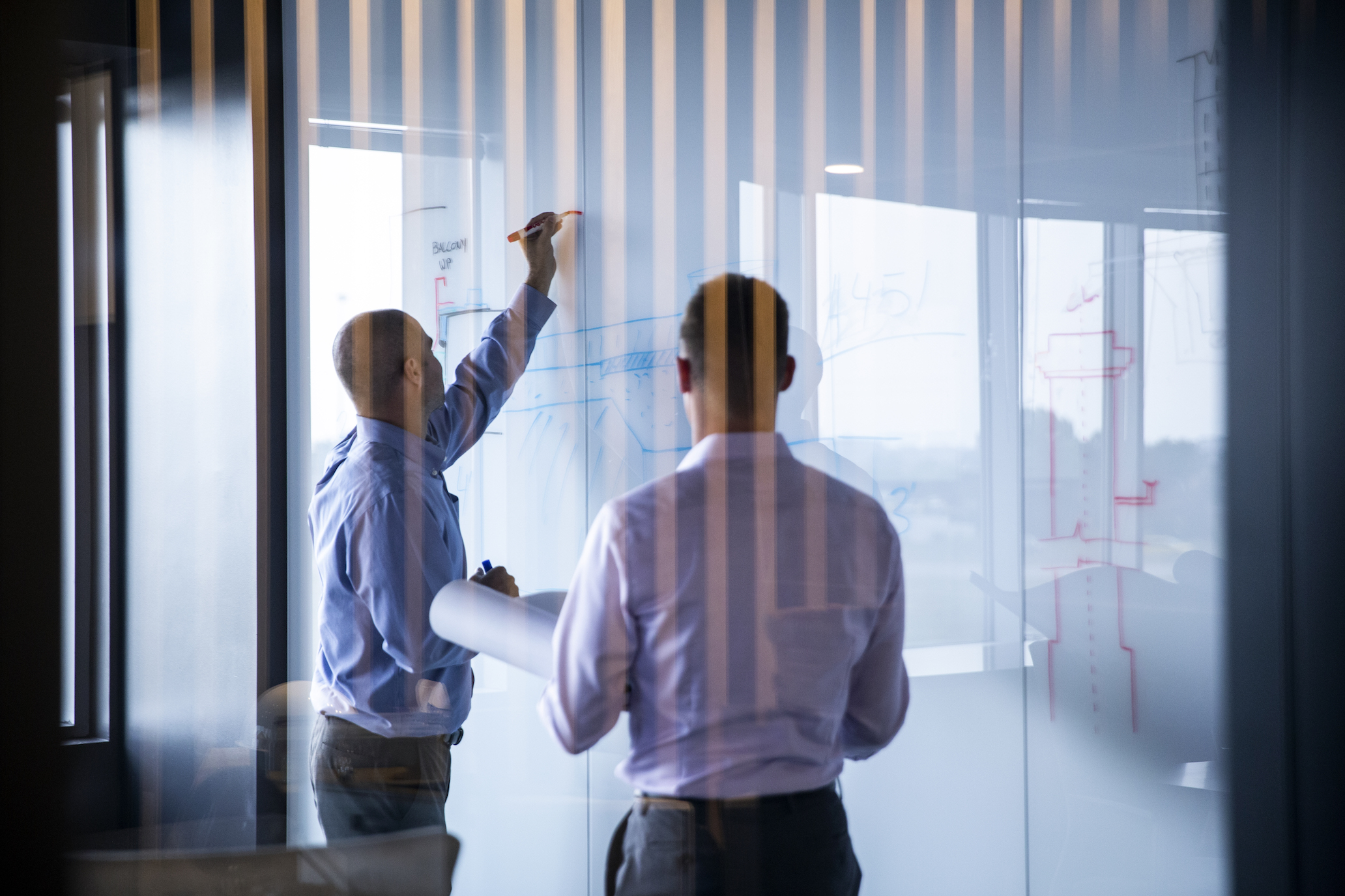 Two employees drawing on whiteboard