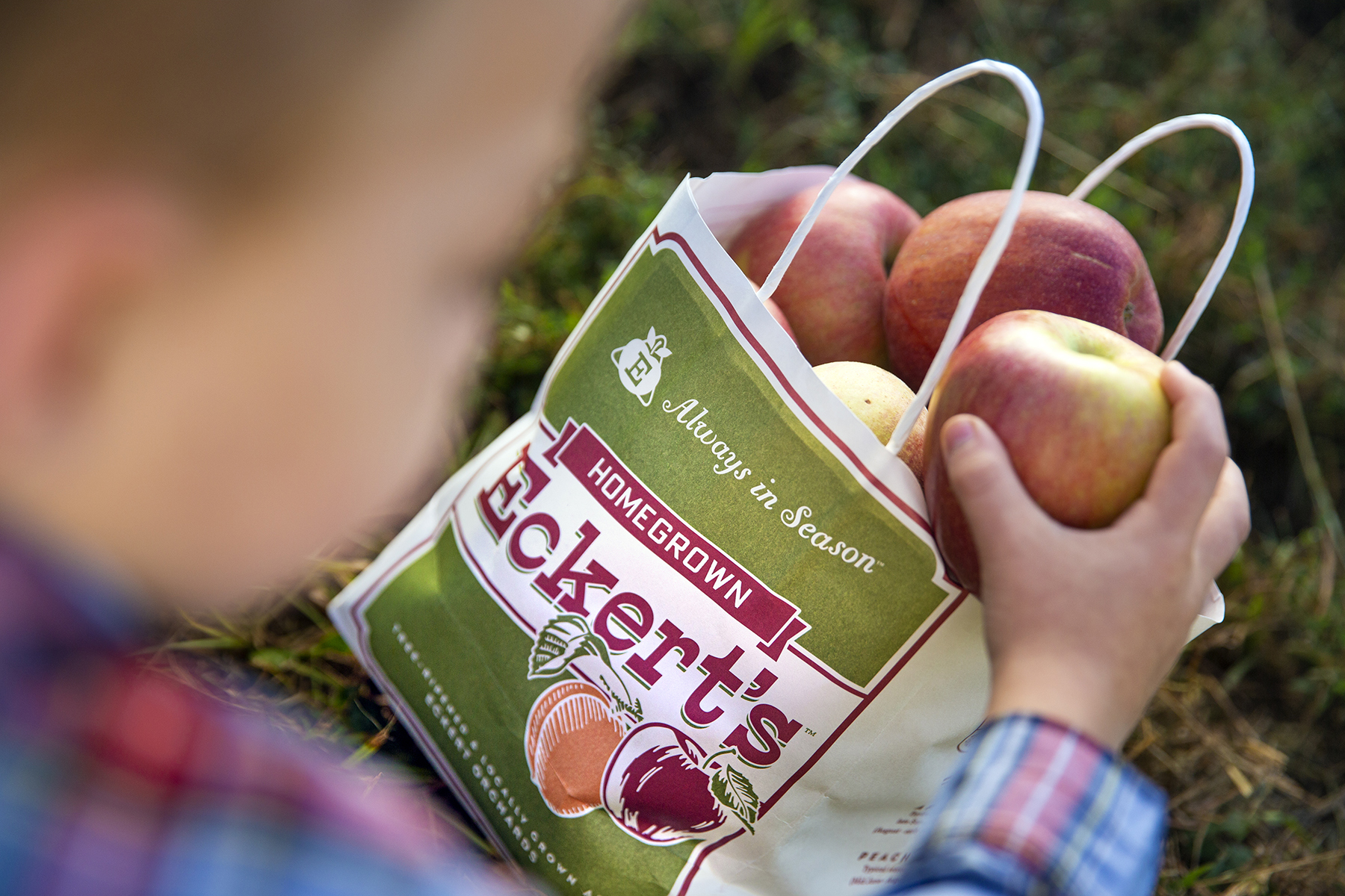 Child placing apple into branded bag